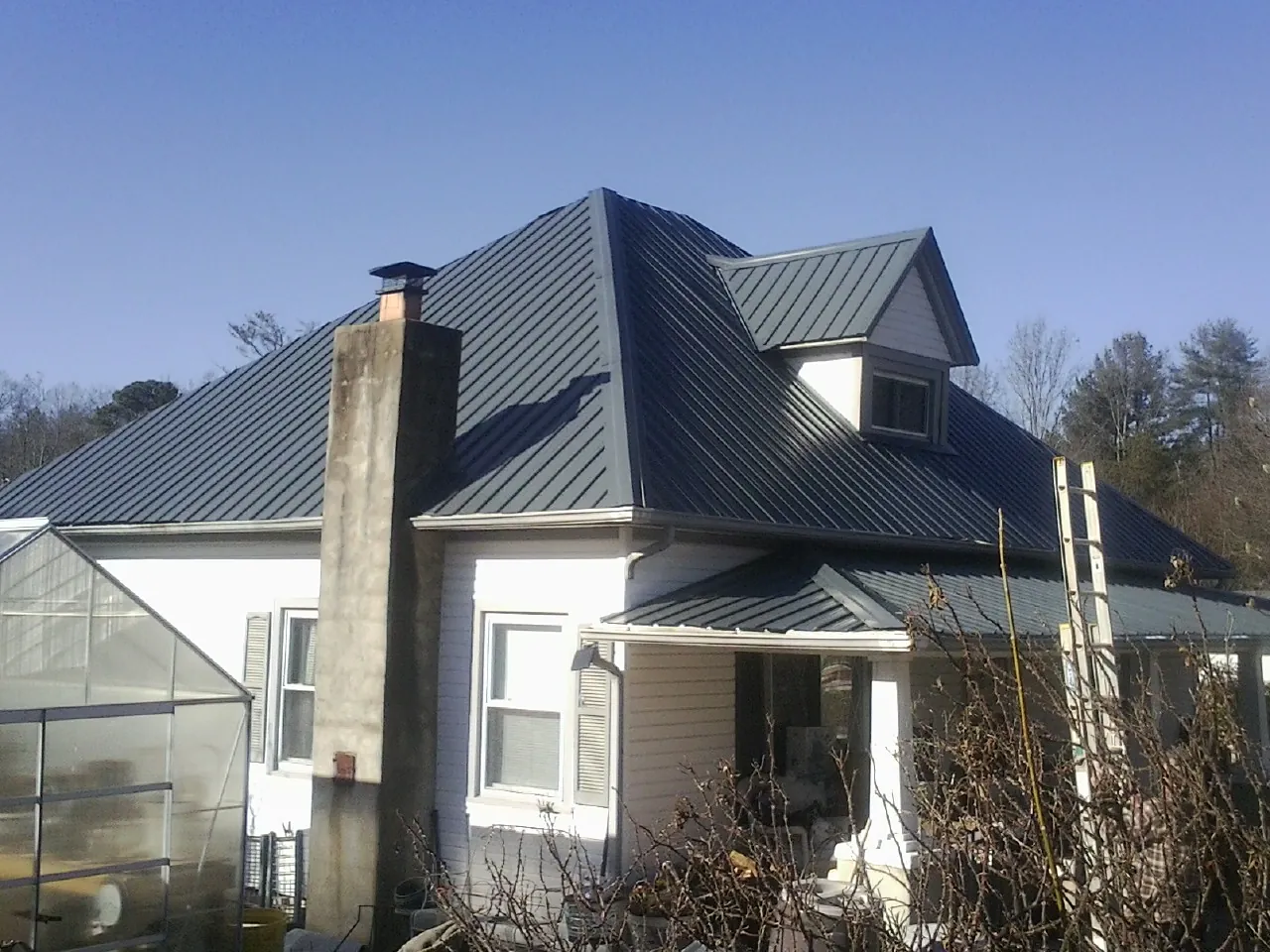 Dark blue standing seam metal roof on a white farmhouse with dormer — Slate & Tile Roof Repair by Roofing Brothers in Clarksboro