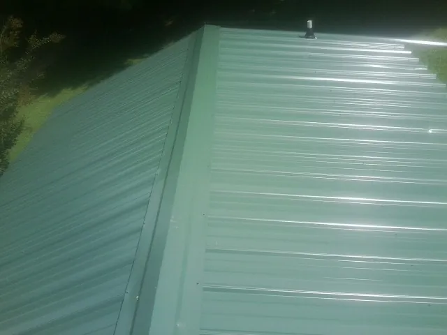 New green metal panels meeting at the ridge of a roof — Flat Roof Repair work by our crew in Clarksboro