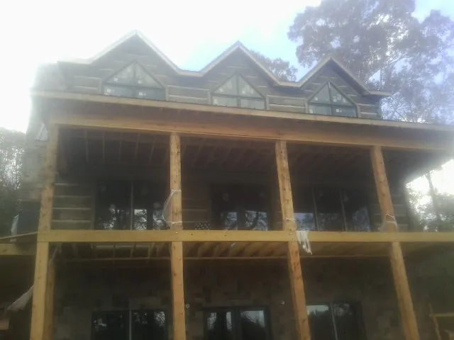 Dormers and porch framing on a large log home under construction — Roof Coating work by our crew in Clarksboro
