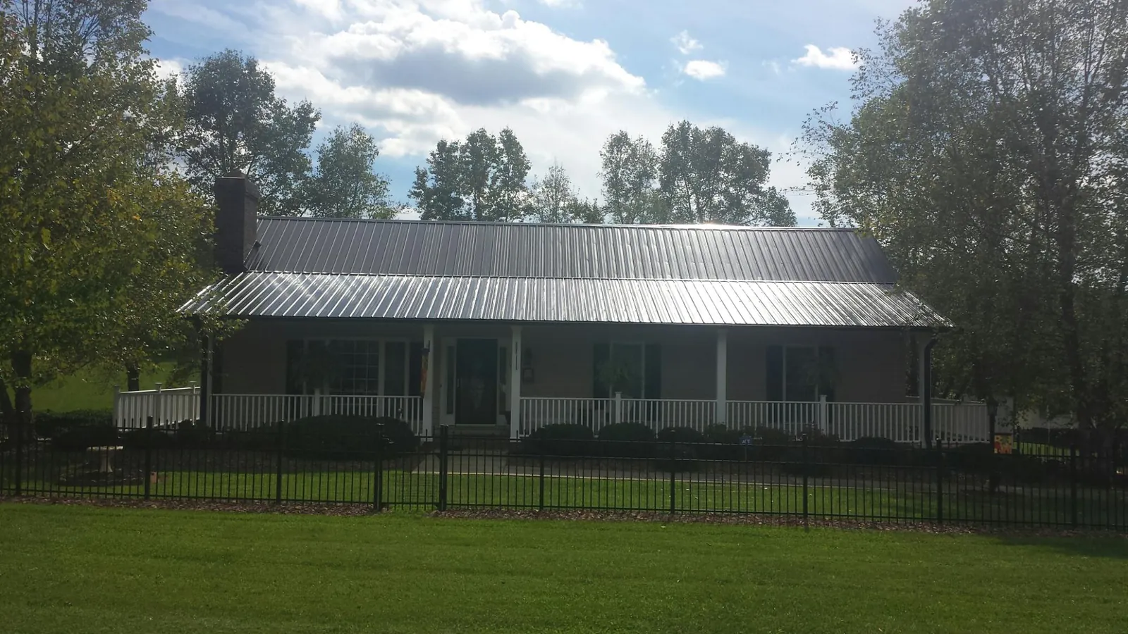 Gray metal roof on a brick ranch with a full width front porch — Gutter Guard Installation work by our crew in Clarksboro