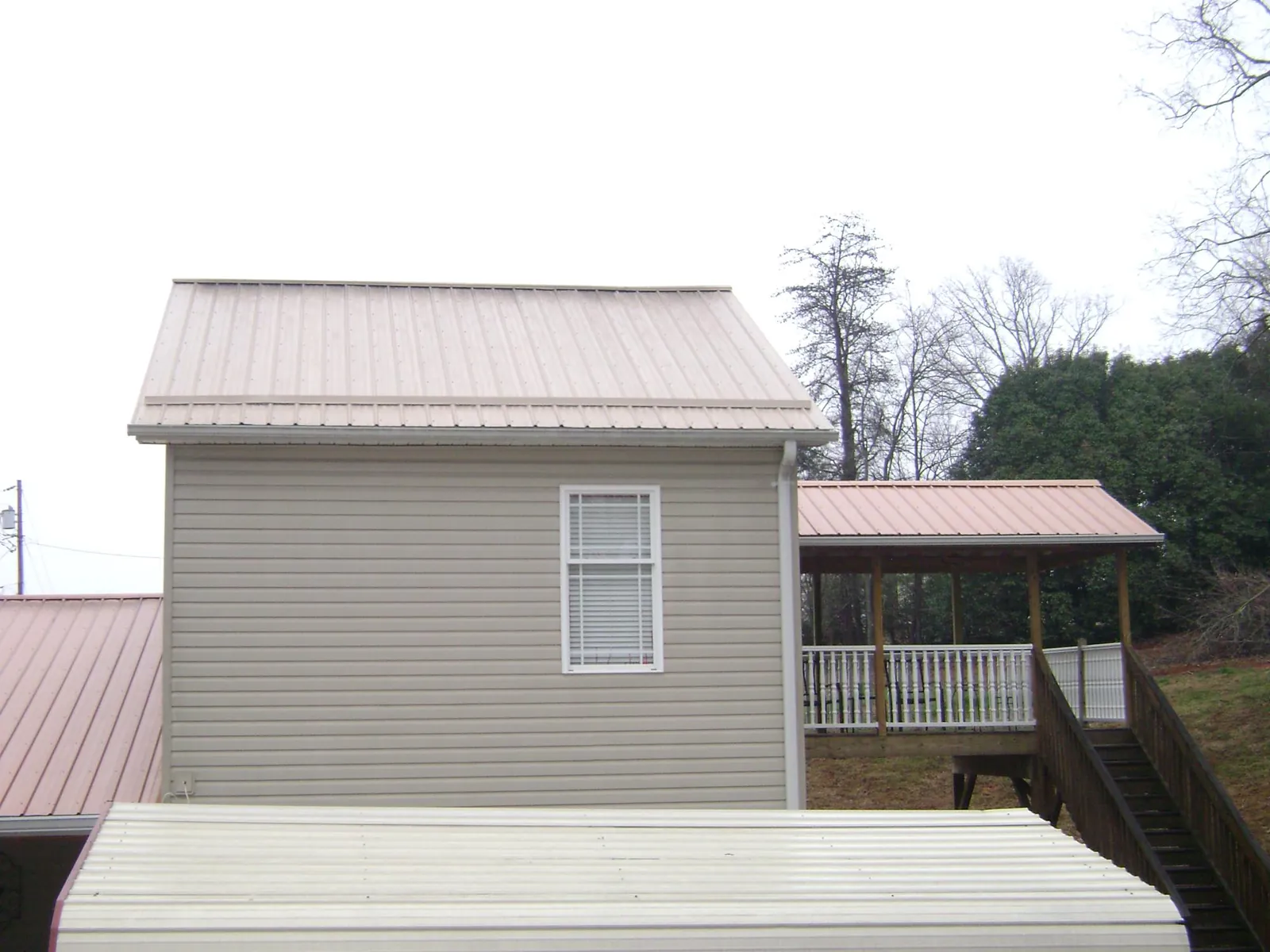 Tan metal roofs on a two story addition and attached porch, from a Roof Replacement job in Clarksboro