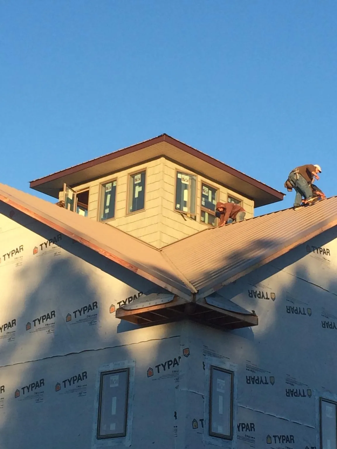 Roofers working around a rooftop cupola on a new metal roof at sunset — Roof Waterproofing in Clarksboro by Roofing Brothers